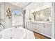 Luxury bathroom with a soaking tub, elegant vanity, and large arched window, creating a spa-like retreat at 5384 Mira Vista Dr, Palm Harbor, FL 34685