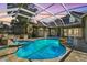 Enclosed pool area features a jacuzzi, waterfall feature, tiled flooring and an outdoor kitchen at 5384 Mira Vista Dr, Palm Harbor, FL 34685