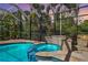 Screened-in pool and spa with tiled surround and lush tropical landscaping beyond at 5384 Mira Vista Dr, Palm Harbor, FL 34685