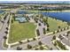 Aerial view of community with tennis courts, swimming pool, and a grassy area next to a lake at 6617 Park Strand Dr, Apollo Beach, FL 33572