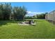 Lush backyard with a stone fire pit and seating area, perfect for outdoor relaxation at 6617 Park Strand Dr, Apollo Beach, FL 33572