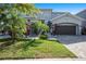 Beautifully landscaped front yard featuring a lush lawn, palm trees, and a charming paver driveway leading to a spacious home at 6617 Park Strand Dr, Apollo Beach, FL 33572