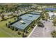 Aerial view of tennis courts with shelters, surrounded by greenery and a parking lot at 6617 Park Strand Dr, Apollo Beach, FL 33572