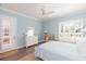 Bright bedroom featuring hardwood floors, neutral walls, a queen bed, and plantation shutters at 6644 Par Ct, Wesley Chapel, FL 33544