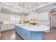 Bright kitchen with a blue island, white cabinetry, modern appliances, and stylish pendant lighting at 6644 Par Ct, Wesley Chapel, FL 33544