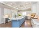 Well-lit kitchen with a blue island, white cabinets, modern appliances, and hardwood floors at 6644 Par Ct, Wesley Chapel, FL 33544