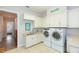 Laundry room with white cabinets, counters, tile floors, and modern washer and dryer at 6644 Par Ct, Wesley Chapel, FL 33544