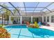 Inviting screened pool features lush landscaping, lounge area, and outdoor dining area with a fire pit for cozy evenings at 6644 Par Ct, Wesley Chapel, FL 33544