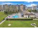 Aerial view of complex featuring community pool, lounge chairs, manicured lawn at 960 Starkey Rd # 5303, Largo, FL 33771