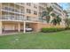 Exterior view of a multi-story condominium with manicured lawn, garage and parking spaces at 960 Starkey Rd # 5303, Largo, FL 33771