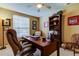 Home office with natural light, a dark wooden desk, and a bookshelf at 14813 Princewood Ln, Land O Lakes, FL 34638