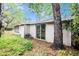 The backyard of the home featuring green grass, a tree, and wooded landscaping at 15165 Waverly St, Clearwater, FL 33760