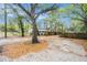 Home exterior featuring a spacious gravel driveway, partial fence, and lush trees surrounding the property at 15165 Waverly St, Clearwater, FL 33760