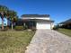 A two-story house with a screen enclosed porch and a brick driveway is framed by two palm trees in the front yard at 16920 Curry Preserve Dr, Punta Gorda, FL 33982