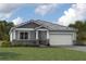 Charming one-story home featuring stone accents, a two-car garage, and manicured lawn under a cloudy blue sky at 18264 Chromata Dr, Venice, FL 34293
