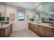 Bathroom with double sinks, wood cabinets, marble floors, large mirror, and windows offering outdoor views at 18604 Arbor Vista Dr, Venice, FL 34293