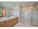 Modern bathroom featuring marble walls, dual walk-in showers, a large mirror, and light wood cabinetry at 18604 Arbor Vista Dr, Venice, FL 34293