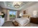 Bright main bedroom with coffered ceiling, chandelier, neutral palette, and a large window providing scenic views at 18604 Arbor Vista Dr, Venice, FL 34293