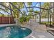 Screened-in pool with rock waterfall feature and mature landscaping offers a tranquil outdoor retreat at 2309 Valrico Forest Dr, Valrico, FL 33594