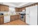 This bright kitchen features wooden cabinetry and white appliances and laminate floor at 2646 Barksdale Ct, Clearwater, FL 33761