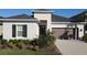 Well-manicured single-story home features a brown garage door, shutters, and lush landscaping at 33410 Castaway Loop, Wesley Chapel, FL 33543