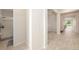 Bright hallway with light wood-look tile flooring leading to a bathroom and living area at 33410 Castaway Loop, Wesley Chapel, FL 33543