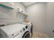 This laundry room features a washer, dryer and wire shelving unit for storage at 33410 Castaway Loop, Wesley Chapel, FL 33543