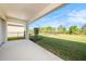 Covered patio with concrete floor overlooks manicured lawn with a partial view of trees at 33410 Castaway Loop, Wesley Chapel, FL 33543