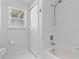 Bright bathroom with a shower over tub, white tile, and a window for natural light at 3629 Mossy Oak Cir, Land O Lakes, FL 34639