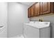 Functional laundry room with white appliances and ample storage with brown cabinets at 3629 Mossy Oak Cir, Land O Lakes, FL 34639