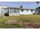 An overgrown backyard shows the structure, in need of landscaping, and partially boarded windows at 596 S Bayshore Dr, Madeira Beach, FL 33708