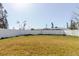 Large, fenced backyard with a mix of green and brown grass, offering ample space for outdoor activities at 596 S Bayshore Dr, Madeira Beach, FL 33708