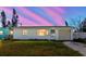 Charming single-story home with a well-maintained lawn and attached garage under a vivid sunset at 596 S Bayshore Dr, Madeira Beach, FL 33708