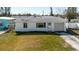 Well-maintained white house with a one-car garage on a lush green lawn under a clear sky at 596 S Bayshore Dr, Madeira Beach, FL 33708