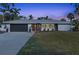 Charming single-story home with an attached garage, red door, and mature landscaping at dusk at 7040 Dr Martin Luther King Jr S St, St Petersburg, FL 33705