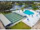 Aerial view of a pool and shuffleboard courts surrounded by mature trees and landscaping at 8220 112Th N St # 206, Seminole, FL 33772