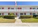 Condo complex exterior showing manicured hedges, white walls, red door trim, and an American flag at 8220 112Th N St # 206, Seminole, FL 33772