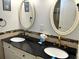 Well-lit bathroom with double sinks, black granite countertop, and dual oval mirrors offers a stylish design at 880 Mandalay Ave # N802, Clearwater Beach, FL 33767