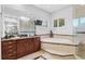Bright bathroom featuring marble countertops, tiled tub, glass shower, vanity, and windows with plantation shutters at 926 Anchorage Rd, Tampa, FL 33602