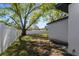 Backyard with a large tree, white vinyl fence, and screened in back porch at 9409 W Perio Pl, Tampa, FL 33612