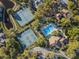 Beautiful aerial view featuring tennis courts, swimming pool, and clubhouse surrounded by lush landscaping at 1020 Lake Avoca Dr, Tarpon Springs, FL 34689