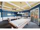 Bright game room with two billiard tables, blue walls, and coffered ceiling with modern pendant lighting and natural light at 1020 Lake Avoca Dr, Tarpon Springs, FL 34689
