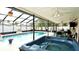 Enclosed pool area featuring a luxurious hot tub, dining area, and rock waterfall for relaxing in a private setting at 10440 Laval St, Spring Hill, FL 34608