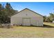 Exterior of white metal outbuilding with roll-up door and walk-in door at 11327 Carter Grove Ln, Thonotosassa, FL 33592