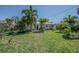 Manicured backyard featuring lush grass, palm trees, and beautiful landscaping at 1740 Grove Dr, Clearwater, FL 33759