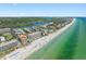 Stunning aerial view of beach condos and waterfront property along pristine white sand beach and blue-green ocean water at 19451 Gulf Blvd # 301, Indian Shores, FL 33785