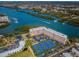 Beautiful aerial view of a large condo building near a bay and tennis courts on a sunny day at 19451 Gulf Blvd # 301, Indian Shores, FL 33785