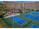 Aerial view of tennis courts, landscaped grounds and a towering beachfront condominium building at 19451 Gulf Blvd # 301, Indian Shores, FL 33785