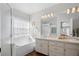 Bright bathroom featuring double sinks, a large mirror, tub, shower, and a window for natural light at 2325 W Del Webb Blvd, Sun City Center, FL 33573