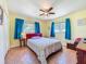 Bedroom featuring a ceiling fan, wood floors, and windows covered by blue curtains at 245 Grove Cir N, Dunedin, FL 34698